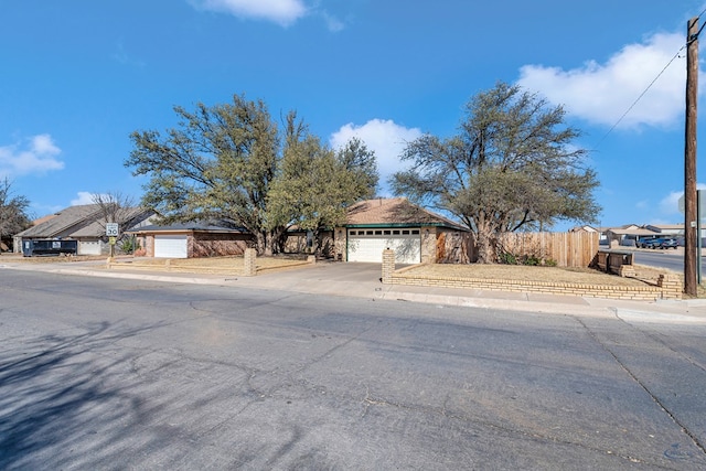 view of front facade with driveway, a garage, and fence