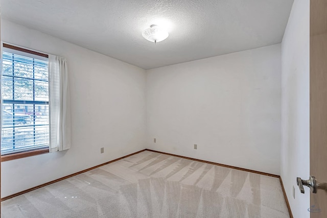 carpeted empty room with a textured ceiling and baseboards