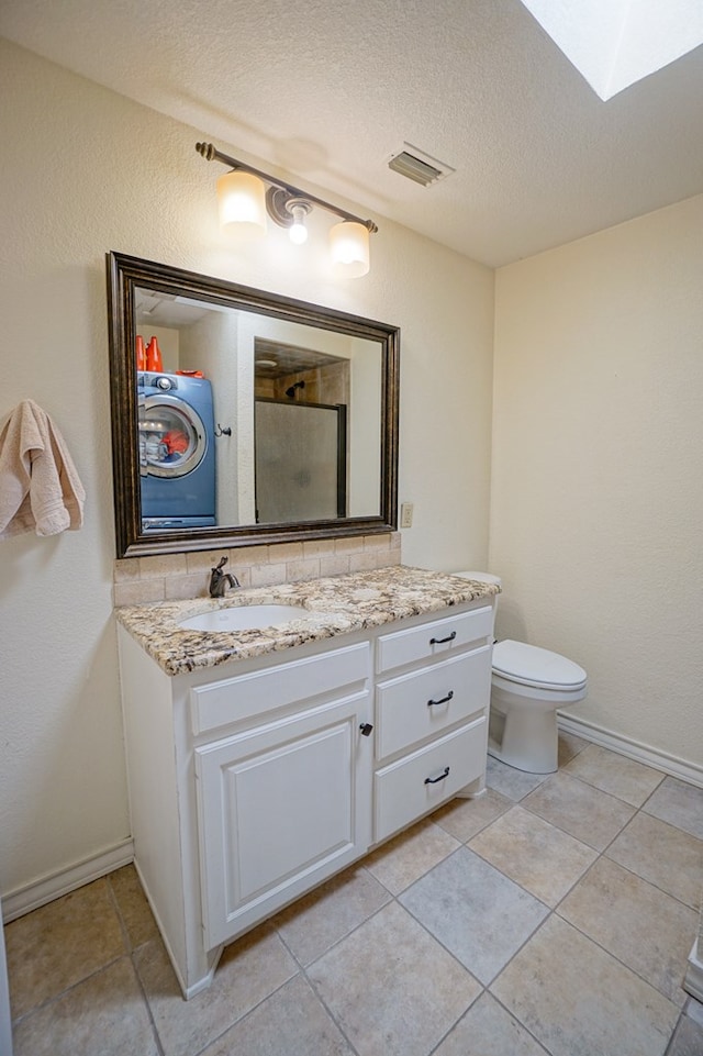 full bathroom featuring a stall shower, a skylight, vanity, toilet, and tile patterned flooring