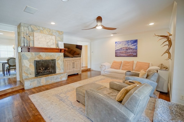 living room featuring dark wood-style floors, ceiling fan, a stone fireplace, baseboards, and recessed lighting