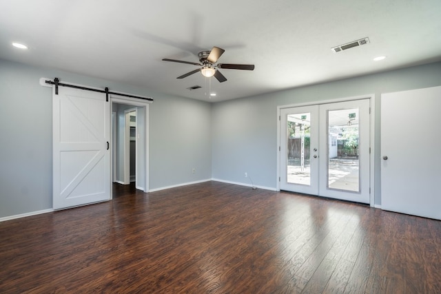 spare room with dark hardwood / wood-style floors, a barn door, ceiling fan, and french doors