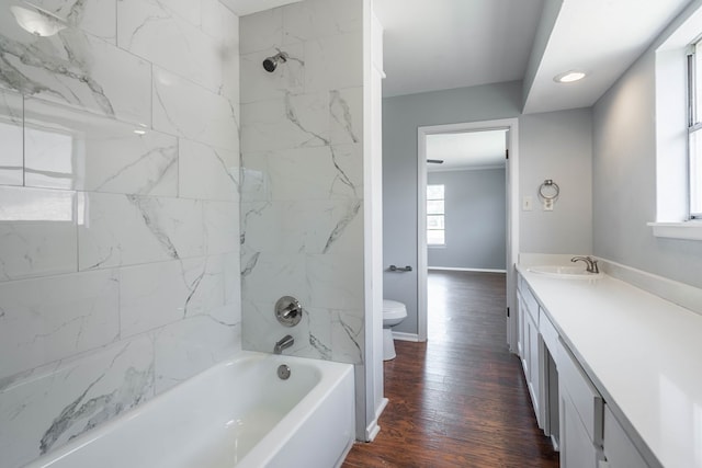 full bathroom featuring hardwood / wood-style floors, vanity, toilet, and tiled shower / bath