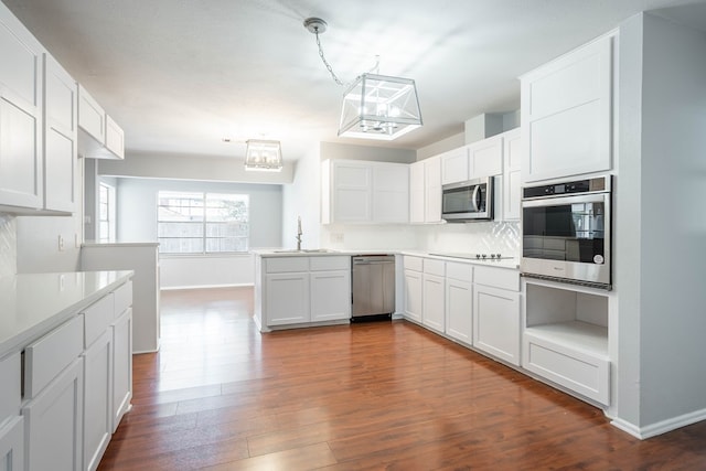 kitchen with appliances with stainless steel finishes, dark wood-type flooring, sink, pendant lighting, and white cabinets