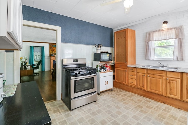 605 W Walnut St, Coleman, TX 76834 - kitchen featuring stainless steel gas stove, black microwave, a ceiling fan, a sink, and light stone counters