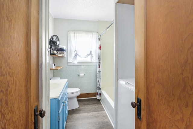 605 W Walnut St, Coleman, TX 76834 - bathroom with toilet, wood finished floors, vanity, shower / bath combo, and tile walls