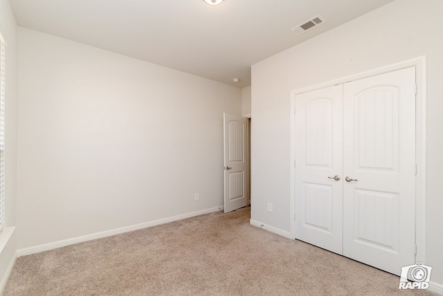 unfurnished bedroom with visible vents, baseboards, a closet, and light carpet