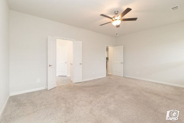 empty room featuring light colored carpet, a ceiling fan, visible vents, and baseboards