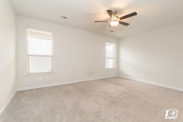 empty room featuring visible vents, a ceiling fan, baseboards, and carpet flooring
