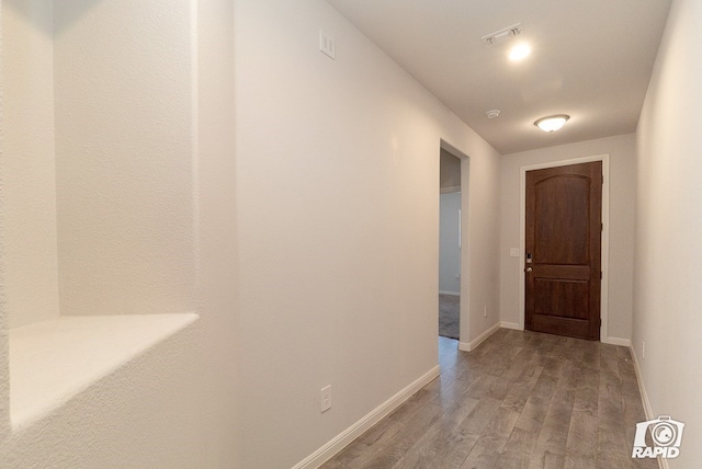 hall with light wood-style floors, baseboards, and visible vents