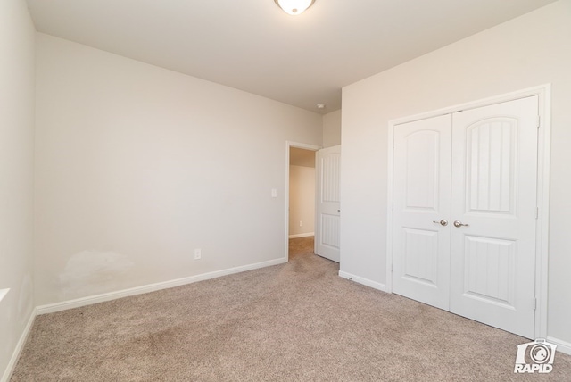 unfurnished bedroom featuring light colored carpet, baseboards, and a closet