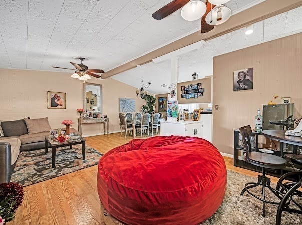 living room with ceiling fan, lofted ceiling with beams, and light wood-type flooring