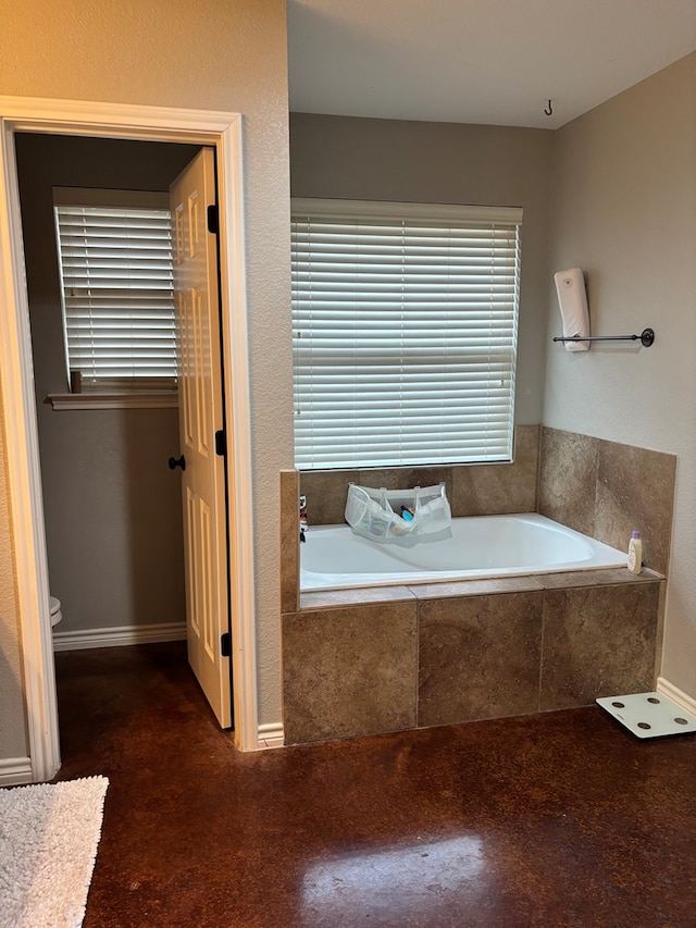 bathroom with tiled tub and toilet