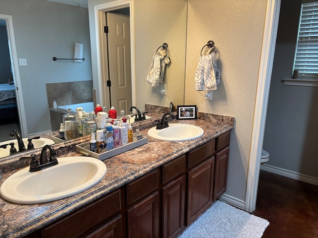 bathroom with vanity, a bath, and toilet