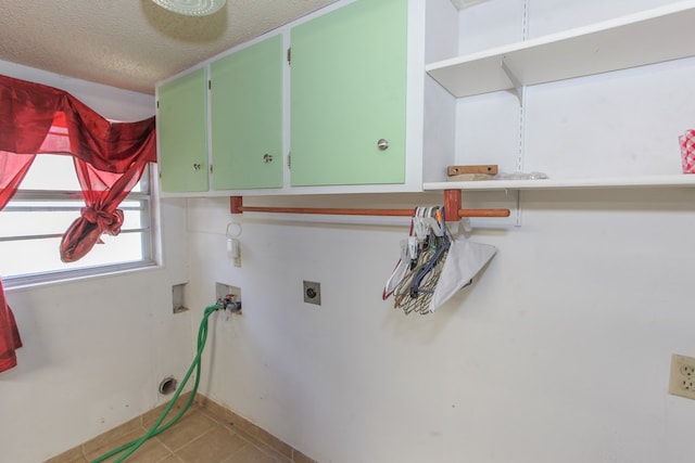 clothes washing area with cabinets, washer hookup, electric dryer hookup, a textured ceiling, and light tile patterned floors