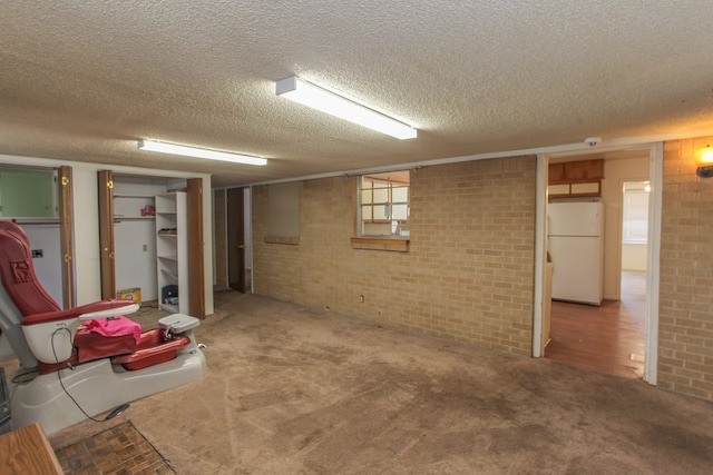 basement featuring carpet flooring, a textured ceiling, and white refrigerator