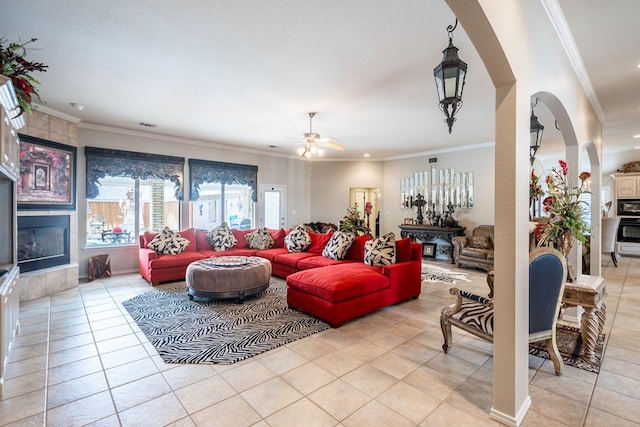 living room featuring light tile patterned floors, crown molding, a fireplace, and ceiling fan