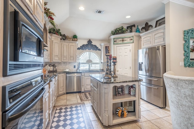 kitchen featuring sink, appliances with stainless steel finishes, backsplash, a center island, and dark stone counters