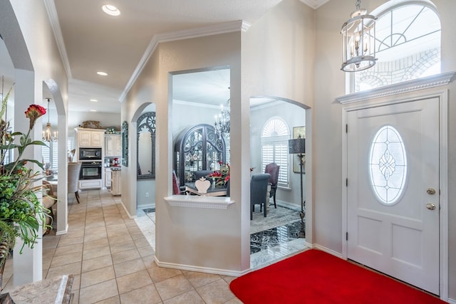 entrance foyer with an inviting chandelier, ornamental molding, and light tile patterned flooring