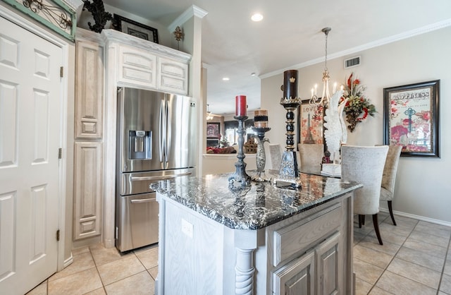 kitchen featuring light tile patterned flooring, ornamental molding, stainless steel fridge, a notable chandelier, and dark stone counters