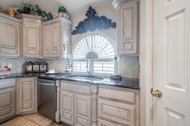 kitchen featuring sink, dark stone countertops, light tile patterned floors, dishwasher, and decorative backsplash