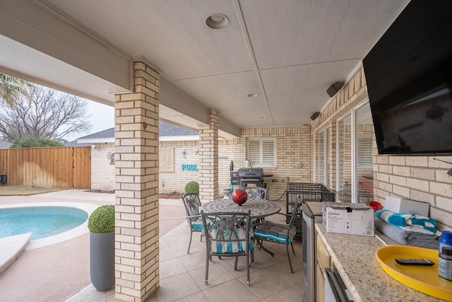 view of patio / terrace featuring a fenced in pool, an outdoor kitchen, an outdoor bar, and grilling area