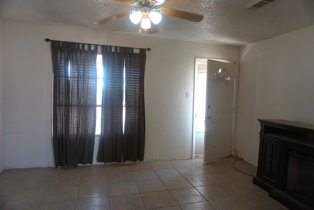 unfurnished living room featuring a textured ceiling, ceiling fan, and light tile patterned flooring