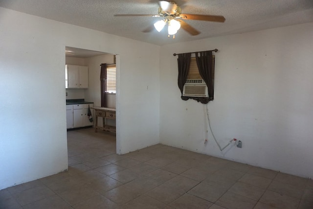 tiled empty room featuring ceiling fan and a textured ceiling