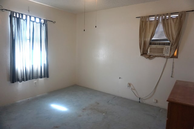 spare room featuring cooling unit, concrete flooring, and a textured ceiling