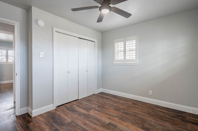 unfurnished bedroom featuring multiple windows, a closet, dark hardwood / wood-style floors, and ceiling fan