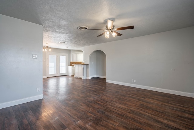 unfurnished living room with dark hardwood / wood-style flooring, ceiling fan with notable chandelier, and a textured ceiling