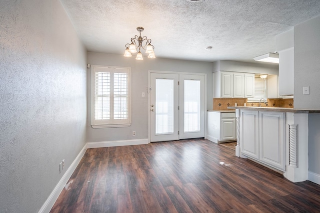 kitchen with white cabinetry, decorative light fixtures, a chandelier, dark hardwood / wood-style floors, and kitchen peninsula