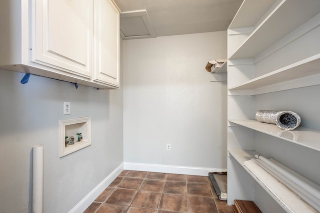 clothes washing area featuring cabinets, hookup for a washing machine, and dark tile patterned flooring