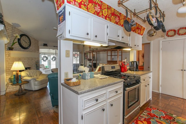 kitchen with stainless steel gas range oven, white cabinets, brick wall, and a textured ceiling