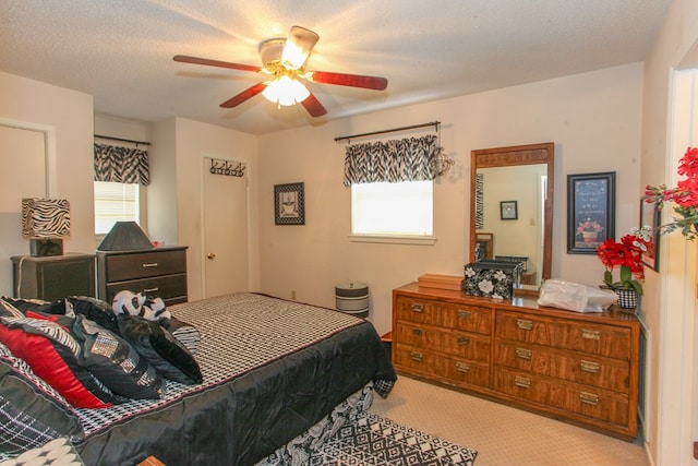 carpeted bedroom featuring ceiling fan and a textured ceiling