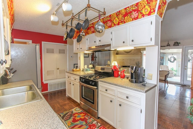 kitchen featuring visible vents, under cabinet range hood, appliances with stainless steel finishes, a textured ceiling, and a sink