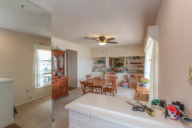 carpeted dining area featuring visible vents, baseboards, a textured ceiling, and ceiling fan