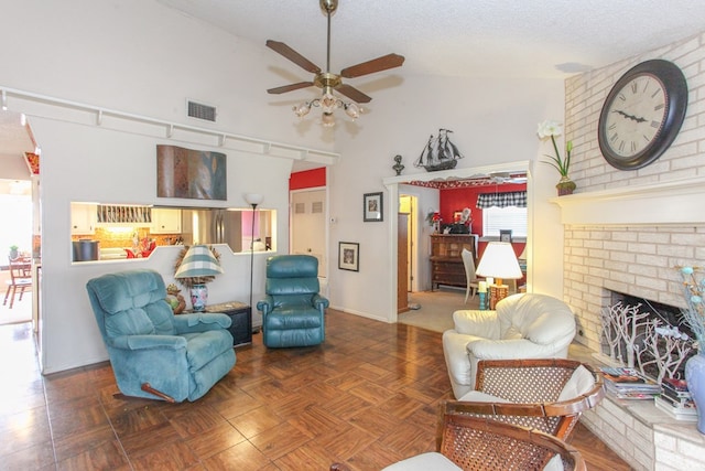 living area featuring visible vents, high vaulted ceiling, a textured ceiling, a brick fireplace, and ceiling fan