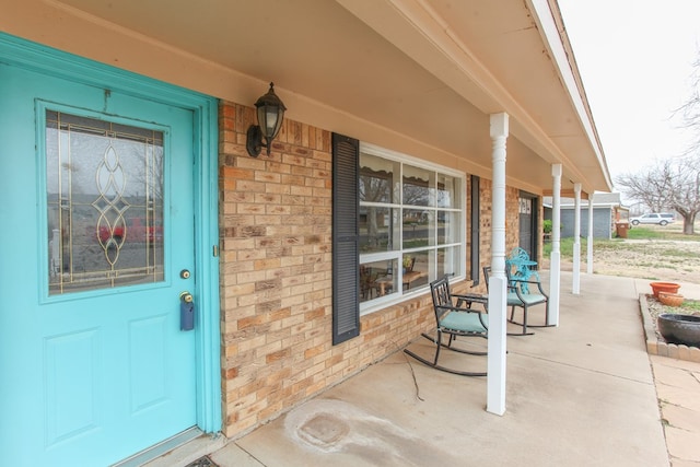 entrance to property featuring brick siding and covered porch