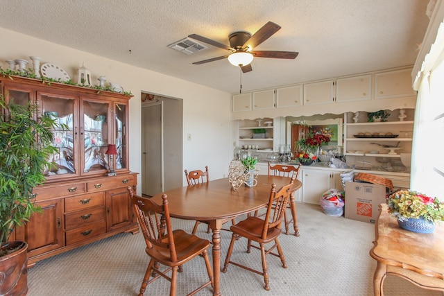 dining room with visible vents, light colored carpet, a textured ceiling, and ceiling fan