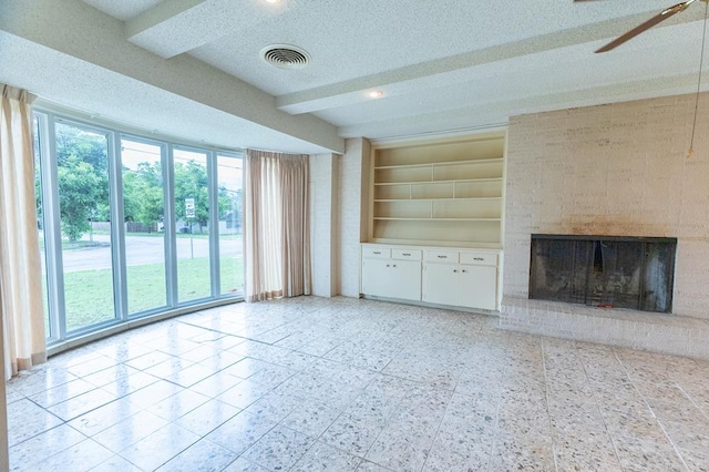1001 W Walnut St, Coleman, TX 76834 - unfurnished living room featuring a brick fireplace, built in features, a textured ceiling, ceiling fan, and beamed ceiling