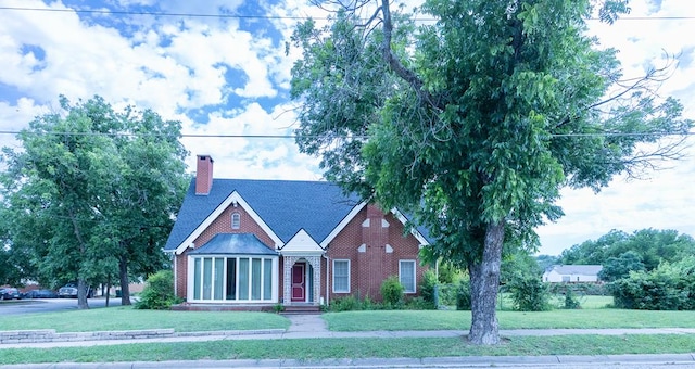1001 W Walnut St, Coleman, TX 76834 - tudor-style house with a front yard, brick siding, a chimney, and roof with shingles