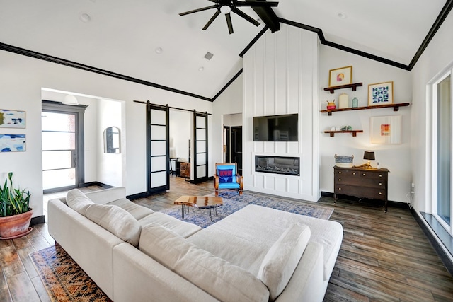 living area with dark wood-style flooring, a barn door, crown molding, a ceiling fan, and baseboards