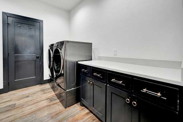 laundry area with light wood-style floors, cabinet space, and washing machine and clothes dryer