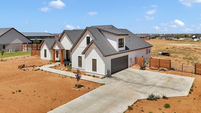 modern farmhouse style home with a shingled roof, driveway, board and batten siding, an attached garage, and fence