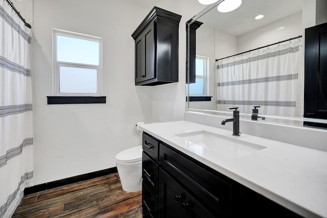 bathroom featuring vanity, curtained shower, toilet, baseboards, and wood finished floors