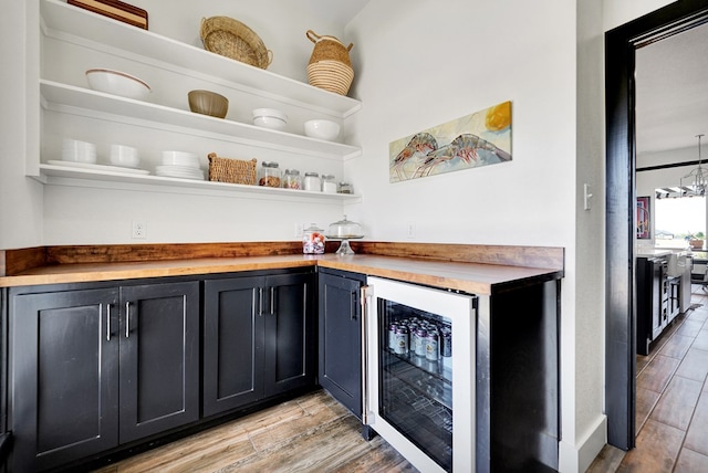 bar with a dry bar, beverage cooler, and light wood-type flooring