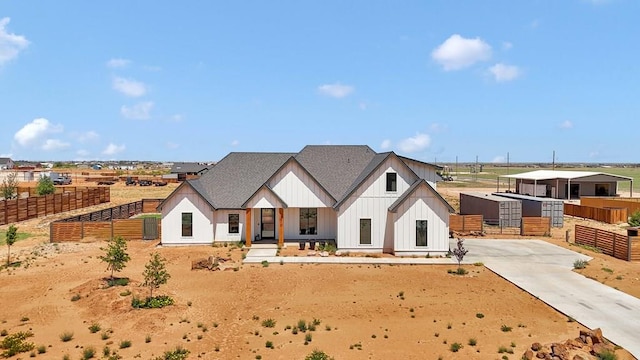 modern inspired farmhouse featuring fence, roof with shingles, board and batten siding, and an outbuilding