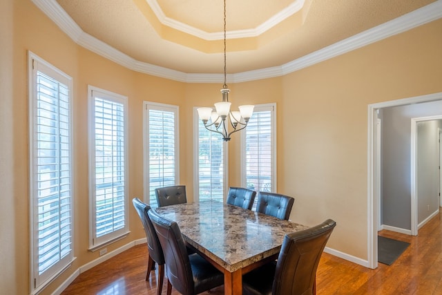 5411 Ridgemont Ct, Midland, TX 79707 - dining area with a tray ceiling, a chandelier, dark wood finished floors, ornamental molding, and plenty of natural light