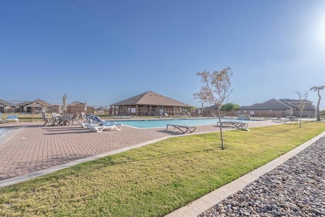 pool featuring a yard, a patio area, and fence