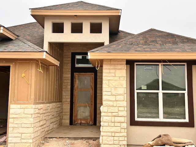 property entrance with a shingled roof and stone siding